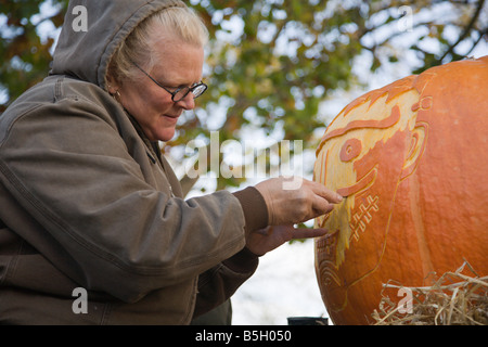 Eine Frau aus Nalls Bauernhofmarkt schnitzt einen Kürbis 2008 Shenandoah Valley Heißluftballon und Weinfest in Virginia. Stockfoto