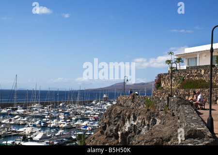 dh PUERTO CALERO LANZAROTE Touristen Urlauber Menschen paar auf Bank mit Blick auf Yachthafen sitzen Stockfoto