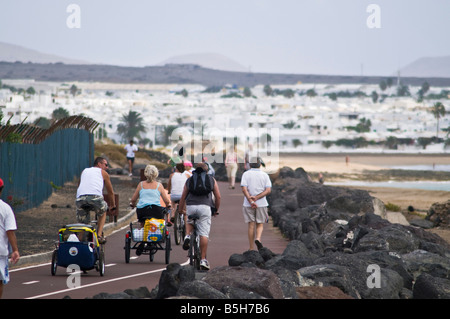 dh PLAYA DE GUACIMETA LANZAROTE Familie Reiten Fahrräder auf Radweg und Menschen zu Fuß entlang der promenade Stockfoto