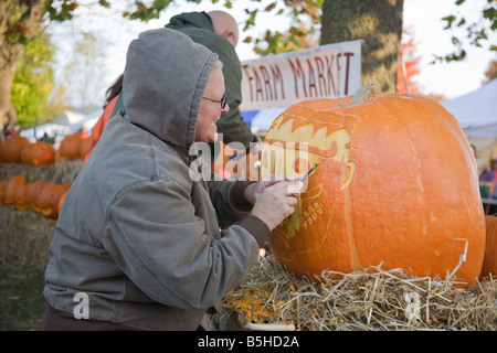 Eine Frau aus Nalls Bauernhofmarkt schnitzt einen Kürbis 2008 Shenandoah Valley Heißluftballon und Weinfest in Virginia. Stockfoto