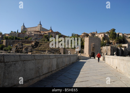 Mann zu Fuß über die Puente de Alcántara zur Stadt von Toledo, Kastilien-La Mancha, Spanien Stockfoto