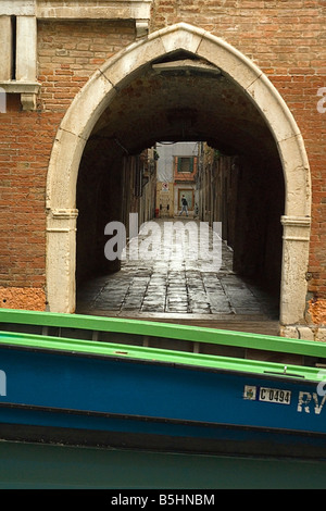 Ein Mann schlendert vorbei am Ende einer Gasse in einem weniger befahrenen Teil von Venedig San Marco Viertel. Stockfoto