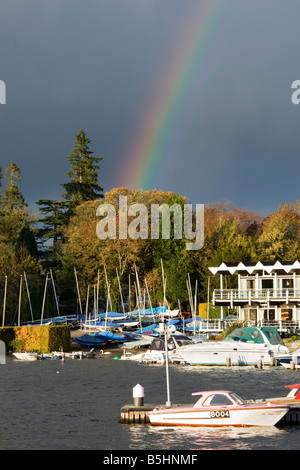 Boote vertäut am Lake Windermere mit Regenbogen im blauen Himmel. Stockfoto