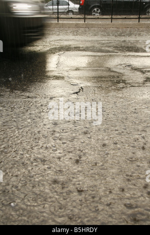 viel Regen Tropfen fallen in Wasser Pfütze auf Straße Stockfoto
