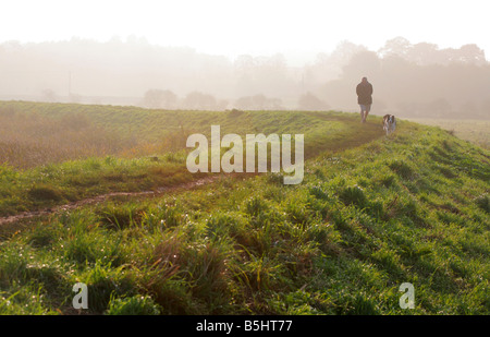 Ein Mann und sein Hund am späten Nachmittag in der Nähe von Cley next am Meer, Norfolk Stockfoto