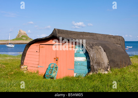 Angelboot/Fischerboot als Schuppen auf Lindisfarne mit der Burg im Hintergrund Northumberland UK Stockfoto