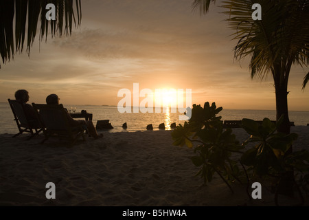 Ein Ehepaar im Ruhestand genießen den Sonnenuntergang auf einem maledivischen Urlaubsinsel im Indischen Ozean Stockfoto