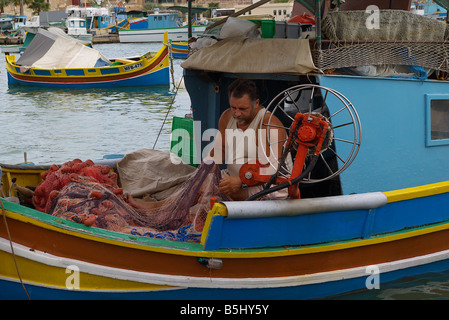 Maltesische Fischer besucht seine Netze auf einem traditionellen Fischerboot. Stockfoto