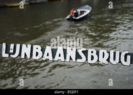 Eine Jolle Kreuzfahrten eine Amsterdam viele Kanäle. Im Vordergrund ist ein Zeichen für Lunbaansbrug, einer Straße im Jordaan. Stockfoto