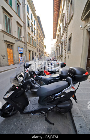 FLORENZ, Italien – Ein Meer von Motorrollern und Motorrädern säumt eine enge Straße im historischen Zentrum von Florenz. Die dicht gepackten Reihen von geparkten Vespas und anderen Motorini zeigen einen typischen Aspekt des modernen italienischen städtischen Lebens vor dem Hintergrund jahrhundertealter Architektur. Stockfoto