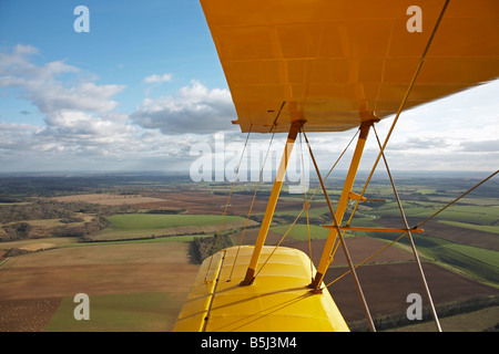 Blick über den Flügel aus dem Cockpit eines Oldtimer Doppeldecker über die englische Landschaft an einem sonnigen Tag Stockfoto