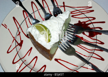 Großzügige Slice von Key Lime Pie mit geschlagener Sahne garnieren Dessert und sechs Gabeln für den Austausch auf einem weißen Teller Stockfoto