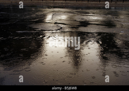 viel Regen Tropfen fallen in Wasser Pfütze auf Straße Stockfoto