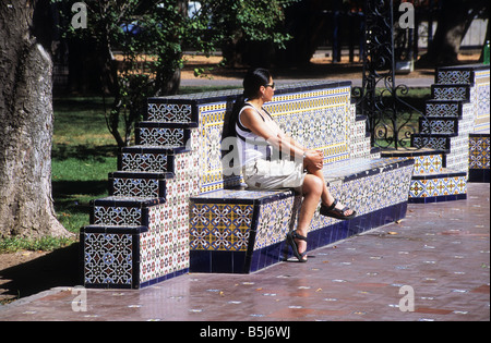 Hispanisches Mädchen sitzt auf einer kunstvoll verzierten Parkbank in Plaza España, Mendoza, Argentinien Stockfoto