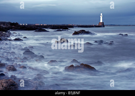 Die südlichen Wellenbrecher und der Leuchtturm am Eingang zum Hafen von Aberdeen, Schottland, in der Dämmerung zu sehen. Stockfoto