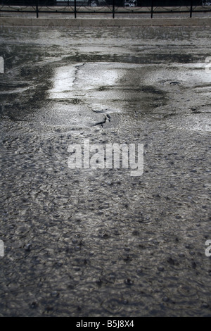 viel Regen Tropfen fallen in Wasser Pfütze auf Straße Stockfoto