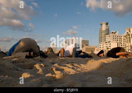 Junge Menschen den Kopf in den Sand vergraben, während humorvolle Ereignis in Jerusalem Strand in Tel Aviv, Israel Stockfoto