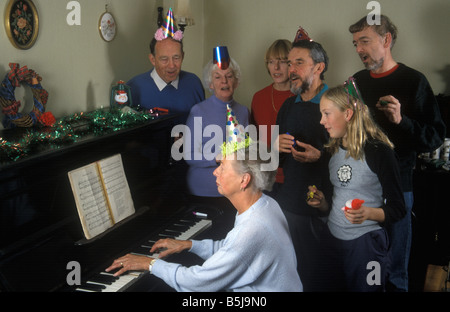 Großfamilie singen Weihnachtslieder runden ein Klavier zur Weihnachtszeit Stockfoto