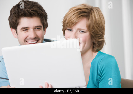 junges Paar versteckt sich hinter Laptop-computer Stockfoto