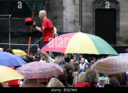 Straßenkünstler auf dem Edinburgh Fringe Festival der Royal Mile entfernt, Einradfahrer Durchführung im Regen Stockfoto