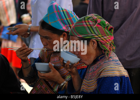 Flower Hmong mit einer Mahlzeit auf dem Markt von Bac Ha Dorf Nord-Vietnam Stockfoto