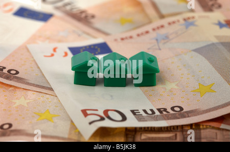 drei grüne Häuser oben auf einem Stapel von 50 Euro-Banknoten-Bargeld Stockfoto