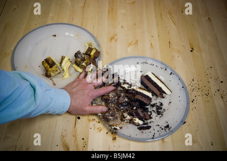 Nahaufnahme einer Mann s Hand graben in Kuchenstücke auf einem Teller Standort veröffentlicht Stockfoto