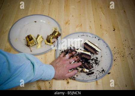 Nahaufnahme einer Mann s Hand graben in Kuchenstücke auf einem Teller Standort veröffentlicht Stockfoto