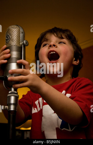 Kleiner Junge singt ein altes Mikrofon Stockfoto