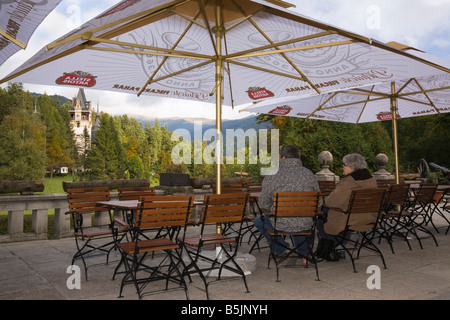 Sinaia Prahova Siebenbürgen Rumänien Leute sitzen unter Sonnenschirm im Café im Freien mit Blick auf Schloss Peles Gelände Stockfoto