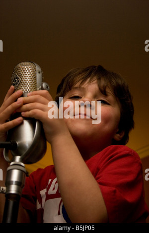 Kleiner Junge singt ein altes Mikrofon Stockfoto