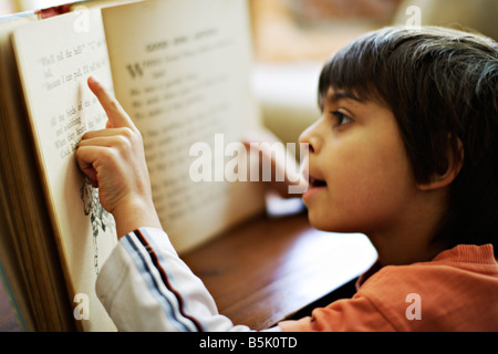 Sechs Jahre alt zeigt junge auf Worte im Buch, als er erfährt, zu lesen Stockfoto