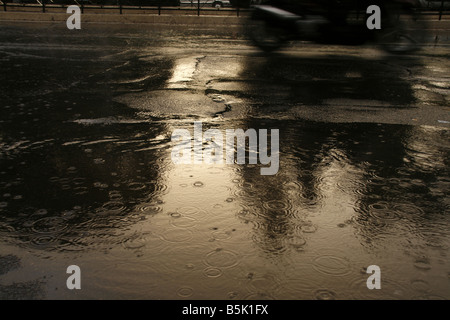 viel Regen Tropfen fallen in Wasser Pfütze auf Straße Stockfoto