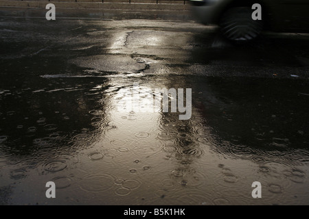 viel Regen Tropfen fallen in Wasser Pfütze auf Straße Stockfoto