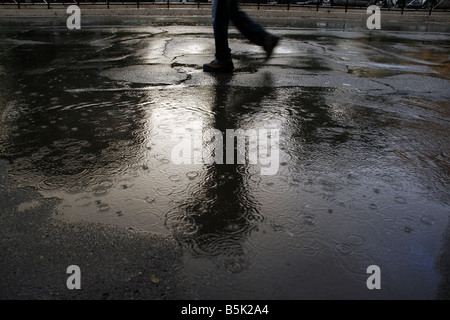 viel Regen Tropfen fallen in Wasser Pfütze auf Straße Stockfoto