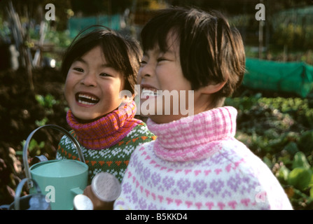 Zwei chinesische Mädchen lachend und kichernd in Kleingärten Stockfoto