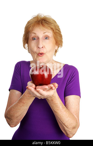 Ältere Dame begeistert die glänzenden roten Apfel sie s, isoliert auf weiss Essen Stockfoto