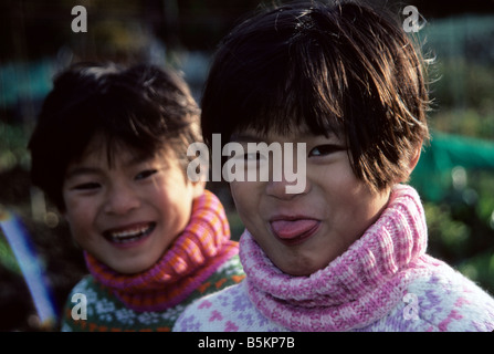 Chinesen zwei Mädchen in eine Zuteilung Grimassen und lachen. Stockfoto