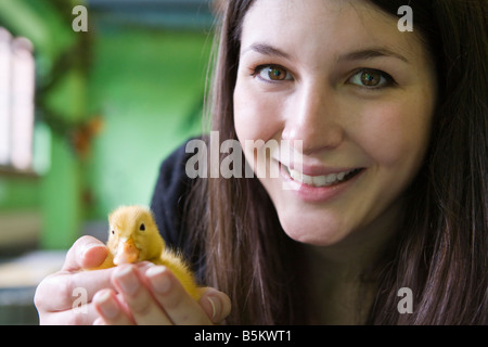 Eine junge Frau, die ein Entlein in der hohlen Hand halten Stockfoto