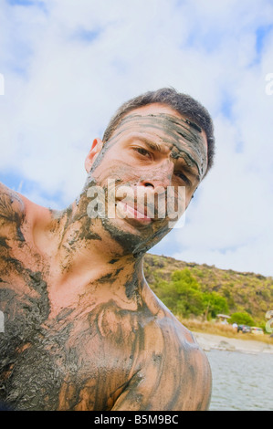 Porträt des Mannes bedeckt im Schlamm stehend in See, Lago Specchio di Venere, Insel Pantelleria, Sizilien, Italien. Stockfoto