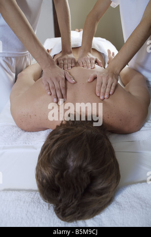Man erhält eine Massage von zwei Frauen. Stockfoto