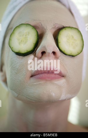 Frau immer eine Gesichtsbehandlung mit Gurken auf den Augen. Stockfoto