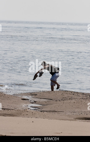 Mann Umfallen mit Füßen im Sand gefangen am Strand mit Schuhen in der Hand am Punkt verschmähen, nördlich Ufer, Fluss Humber, Hull, bis Auslösung, schwankt, Stockfoto