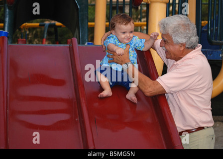 Ein Großvater spielt mit seinem Baby-Enkel in der Kinderspielplatz. Stockfoto
