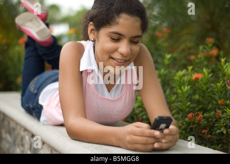 Ein junger Teenager Latina sendet eine Text-Nachricht/e-Mail von einem Handy. Stockfoto