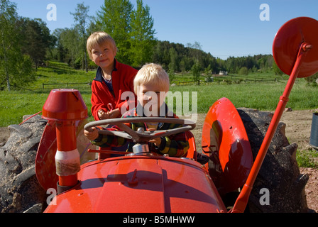 Jungen spielen auf einen alten Traktor auf einem Bauernhof Stockfoto