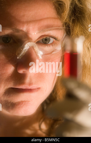 Wissenschaftlerin untersucht eine rote Lösung in einem Reagenzglas. Stockfoto