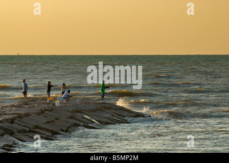 Angeln am Wellenbrecher bei Sonnenaufgang Seawall Boulevard Galveston Texas USA Stockfoto