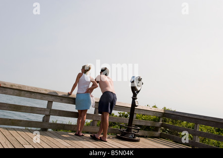 Junges Paar in der Nähe eines binokularen Gerät auf einem Holzsteg am Strand, Blick über den Zaun am Wasser Stockfoto