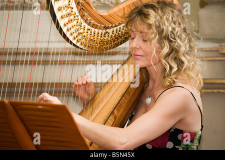 hübsche blonde Frau spielt klassische Harfe Stockfoto